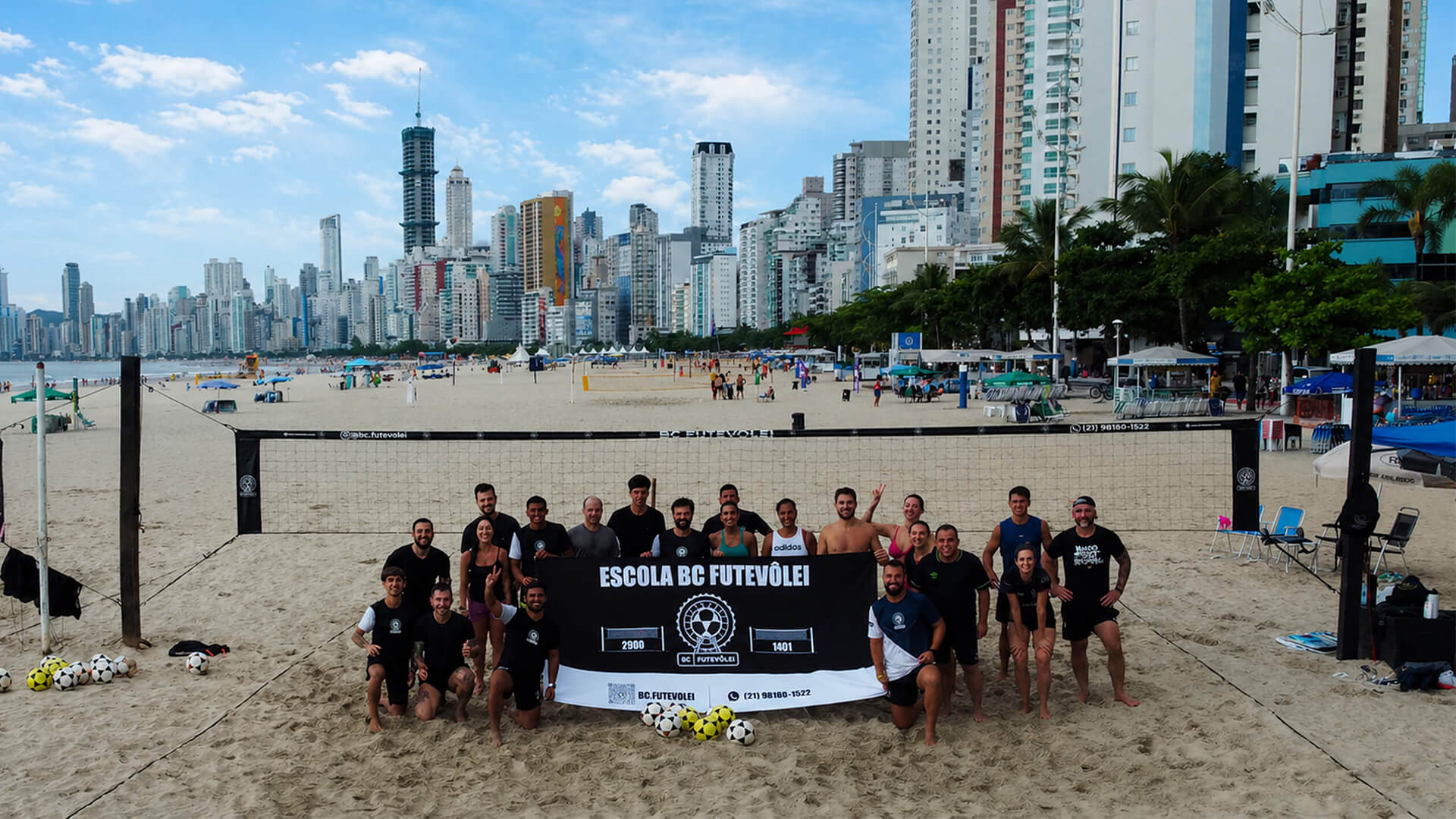 Turma da BC Futevôlei reunida na areia, com os prédios de Balneário Camboriú ao fundo